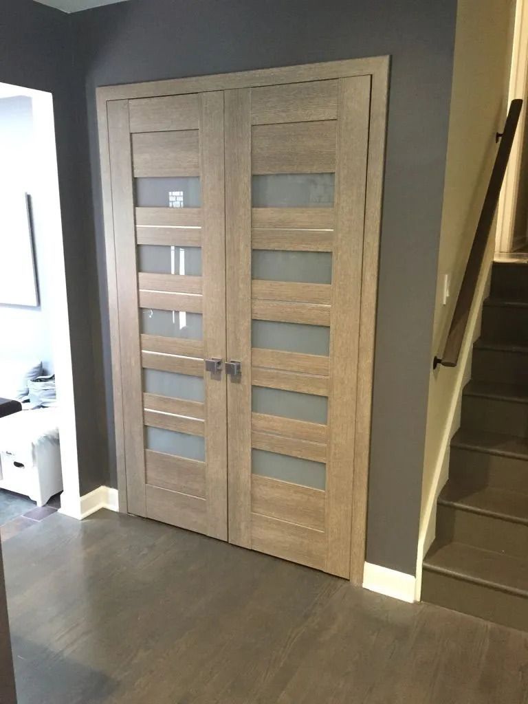 Wooden double doors with frosted glass panels, gray walls, and staircase.