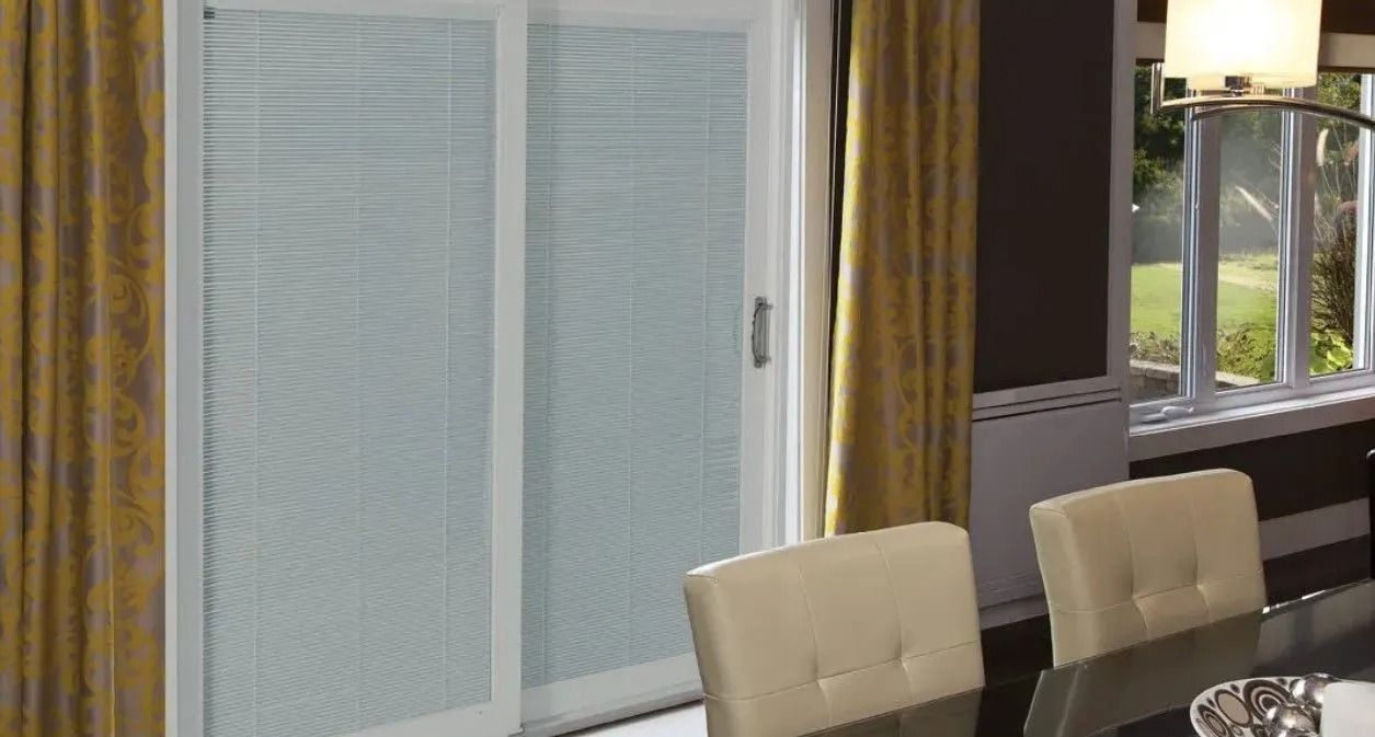 Sliding glass door with blinds and yellow curtains in a dining room.