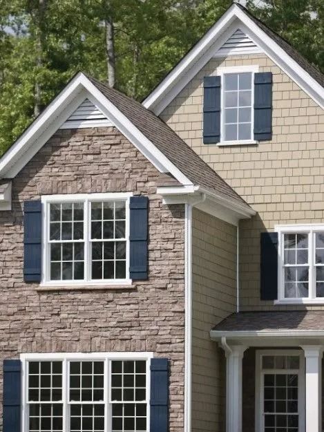 Two-story house with stone and tan siding, white trim, and navy shutters.