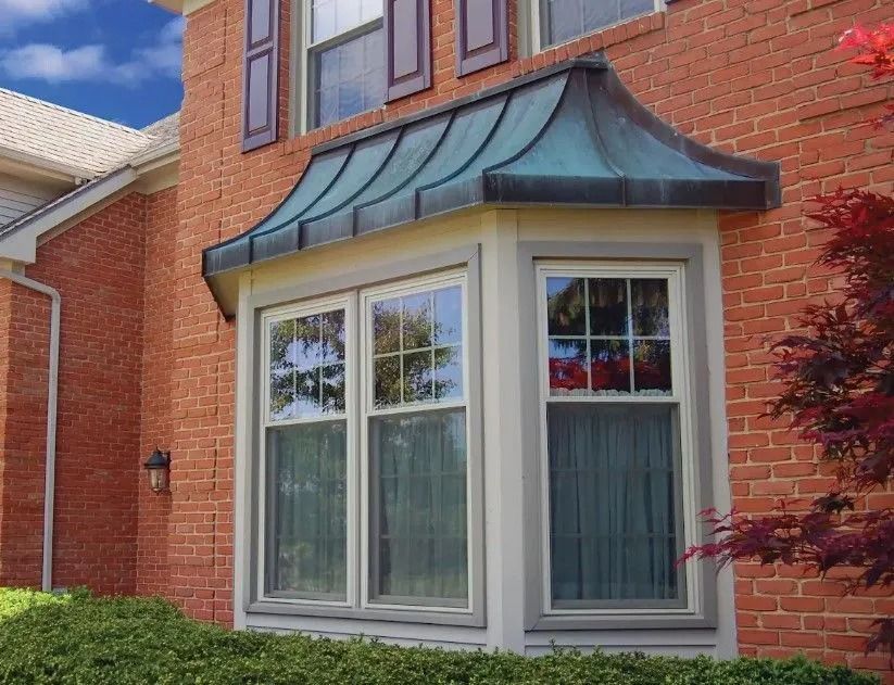 Brick house with a bay window and a copper-colored roof.