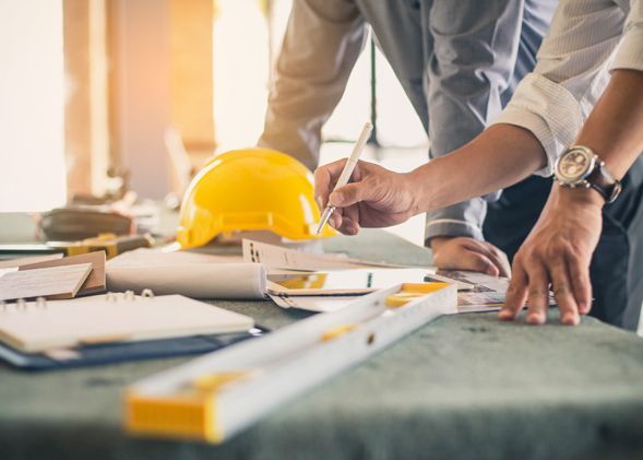 Two men are working on a construction project at a table.