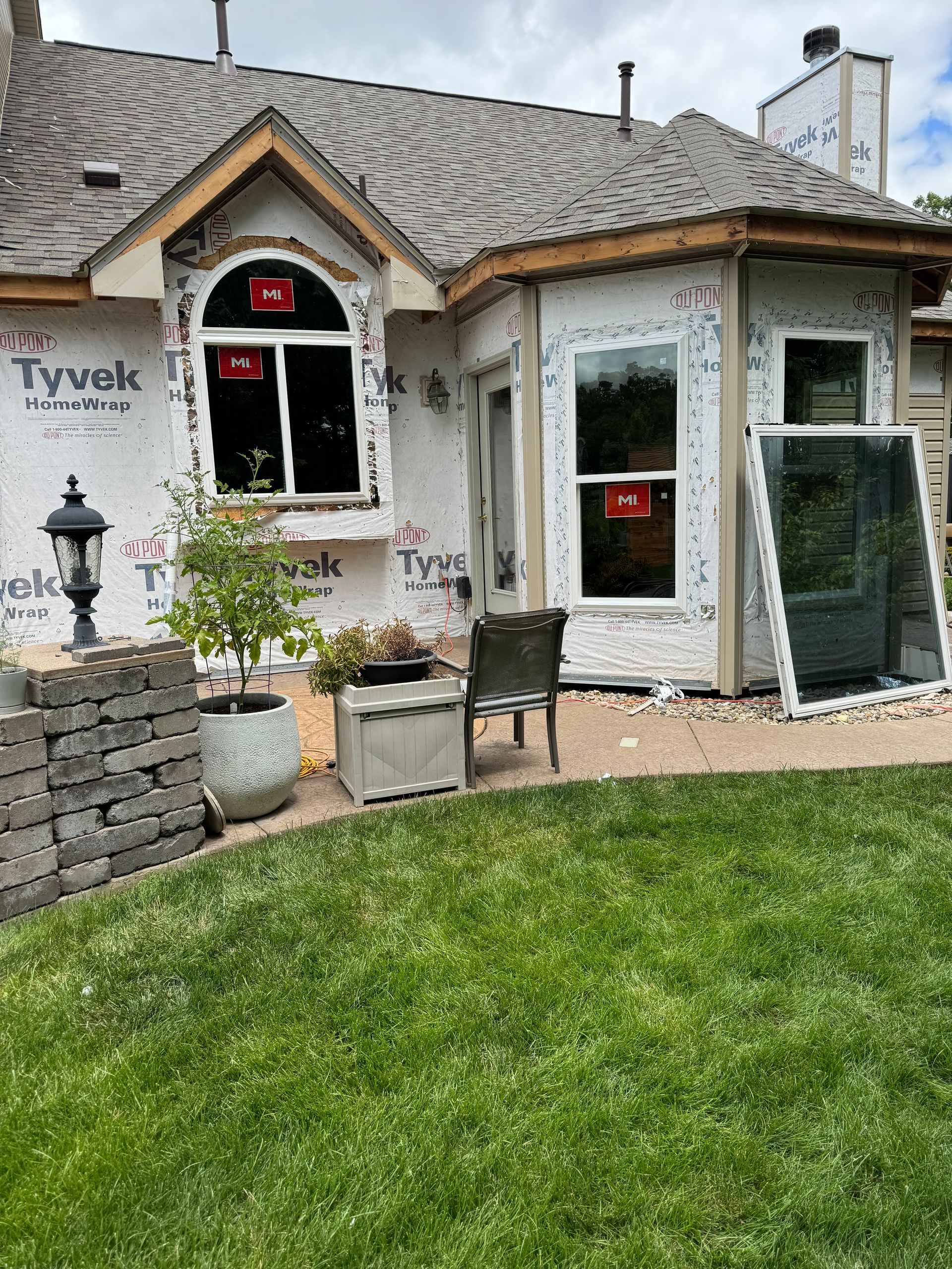 A house with a lot of windows and a patio in front of it.