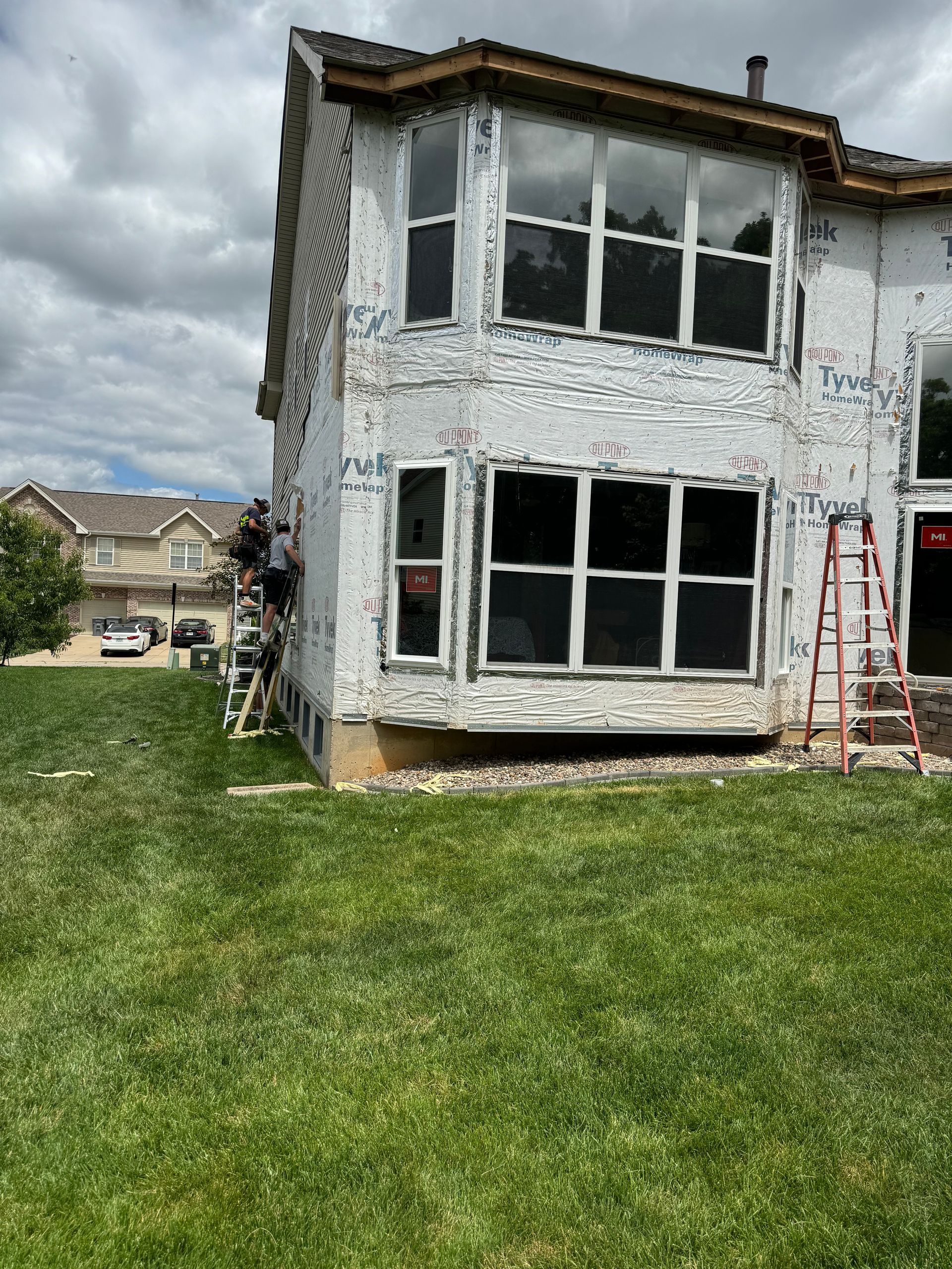 A large white house with a lot of windows is being remodeled.