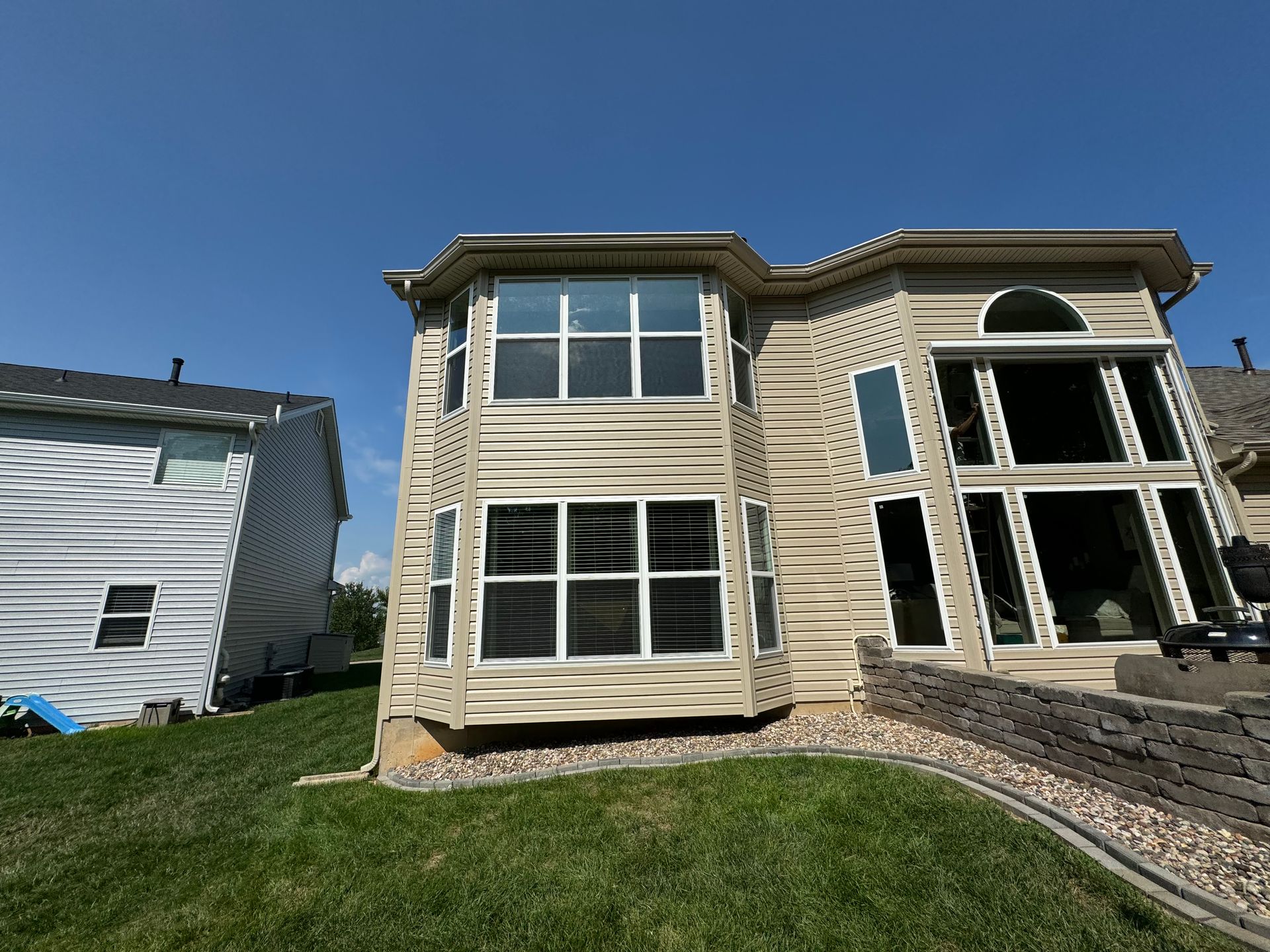 A large house with a lot of windows is sitting on top of a lush green lawn.