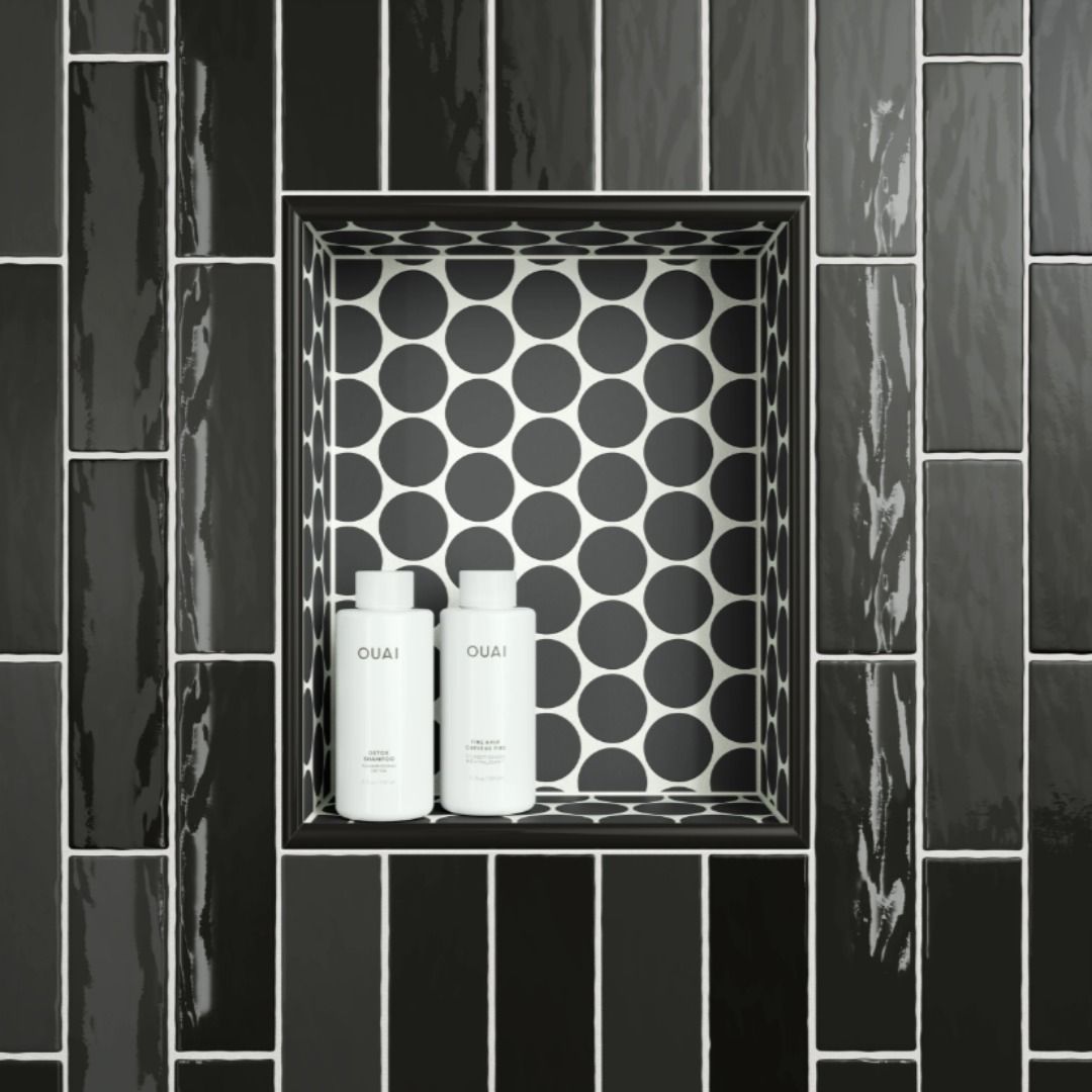 Black tile shower niche with bottles, surrounded by black and white patterned tile.