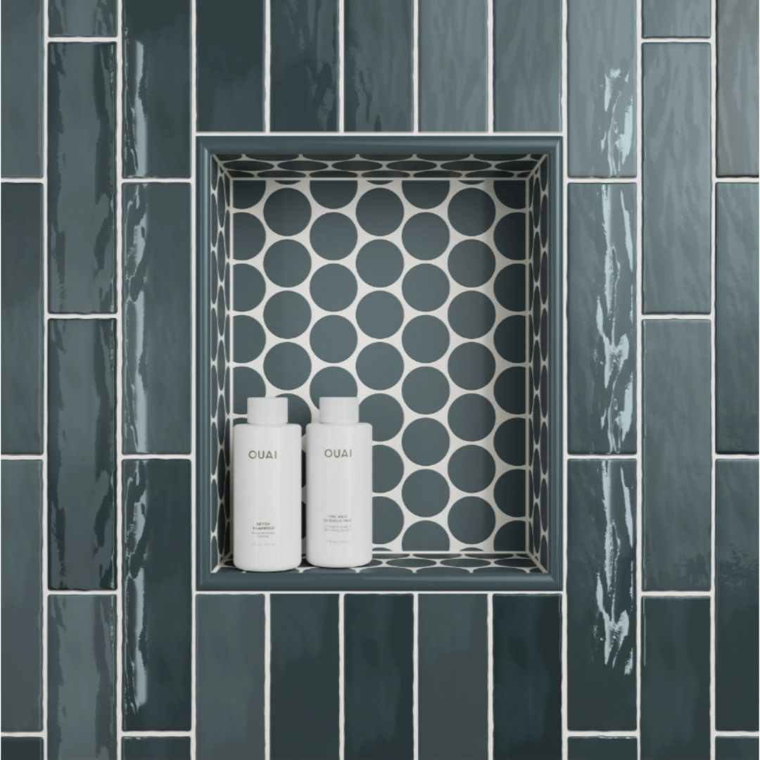 Shower niche with blue-gray rectangular tiles and a circular tile backing, holding two white shampoo bottles.