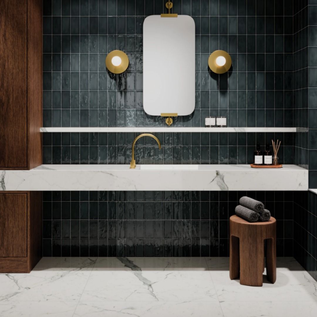 Modern bathroom with dark teal tile, marble vanity, gold fixtures, and wooden accents.