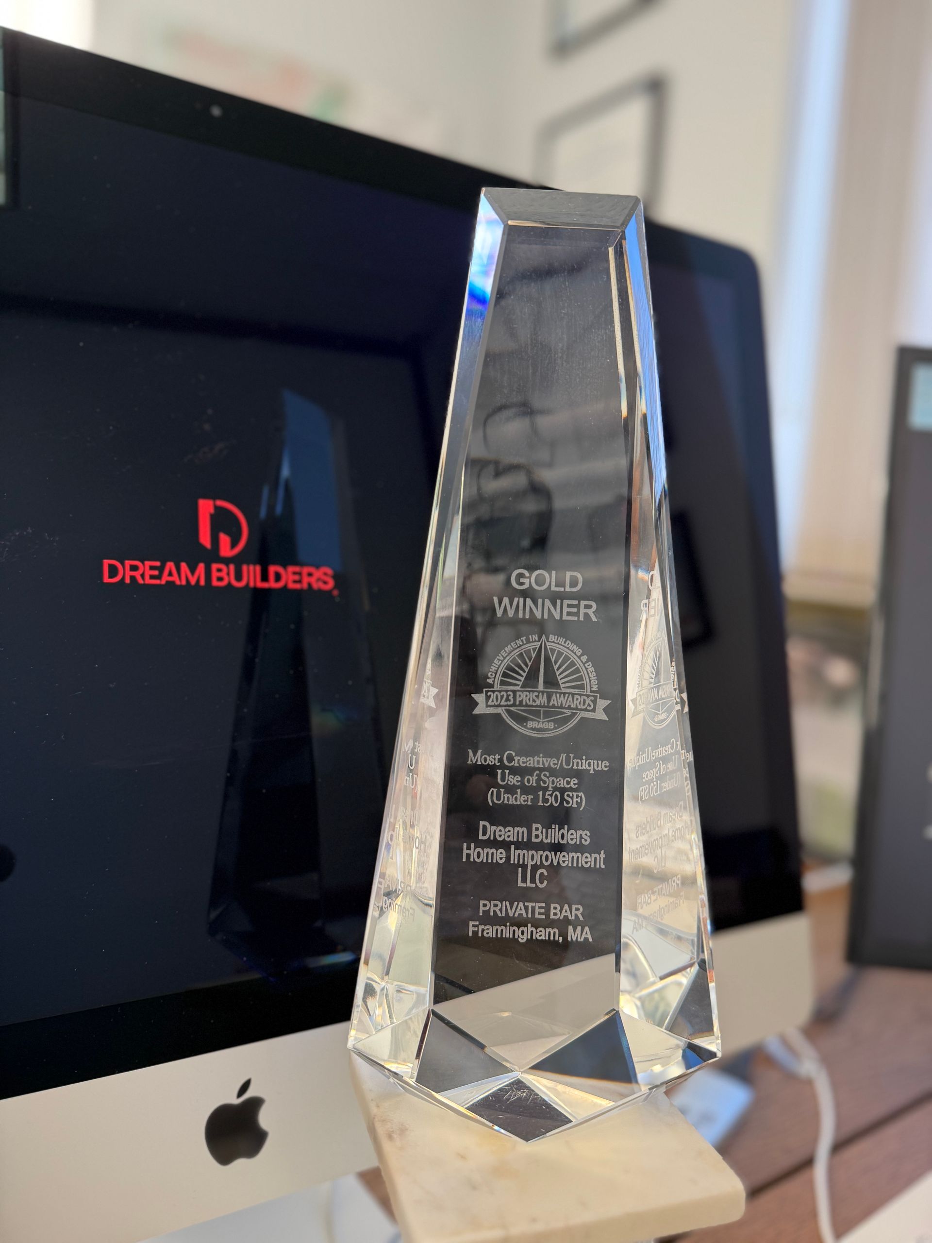 Crystal award in front of a computer screen displaying Dream Builders logo; Gold Award is engraved on it.