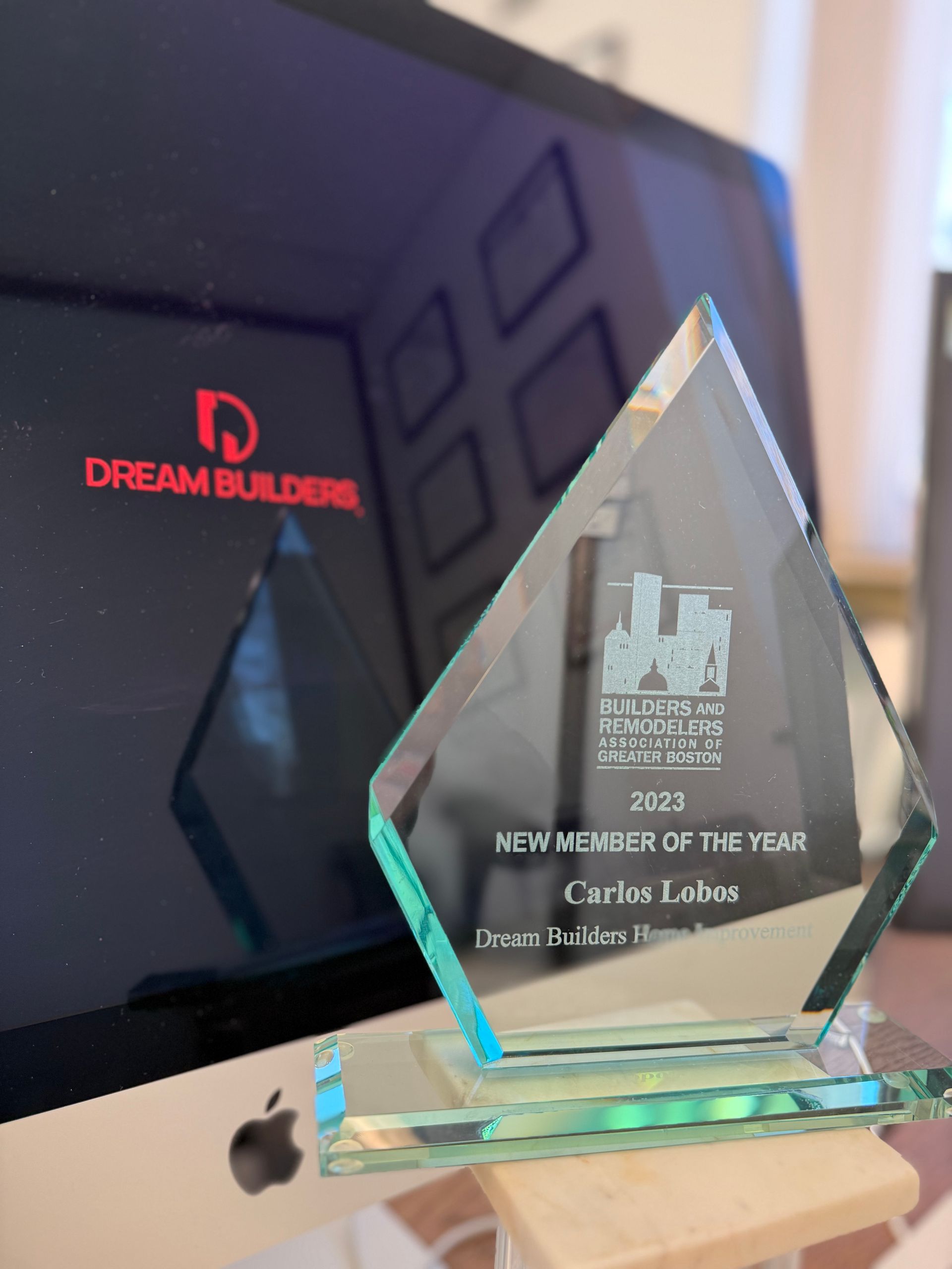Glass award for New Builder of the Year, next to a computer displaying the Dream Builders logo.