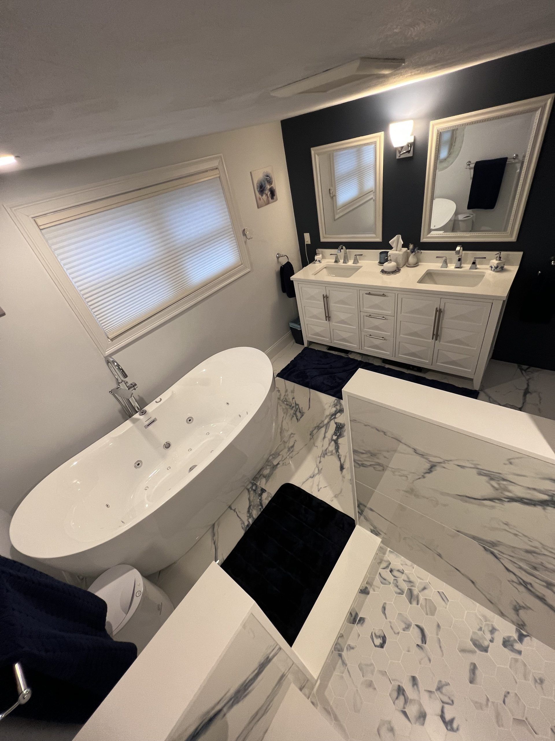 Luxurious bathroom with soaking tub, double vanity, and marble tile.