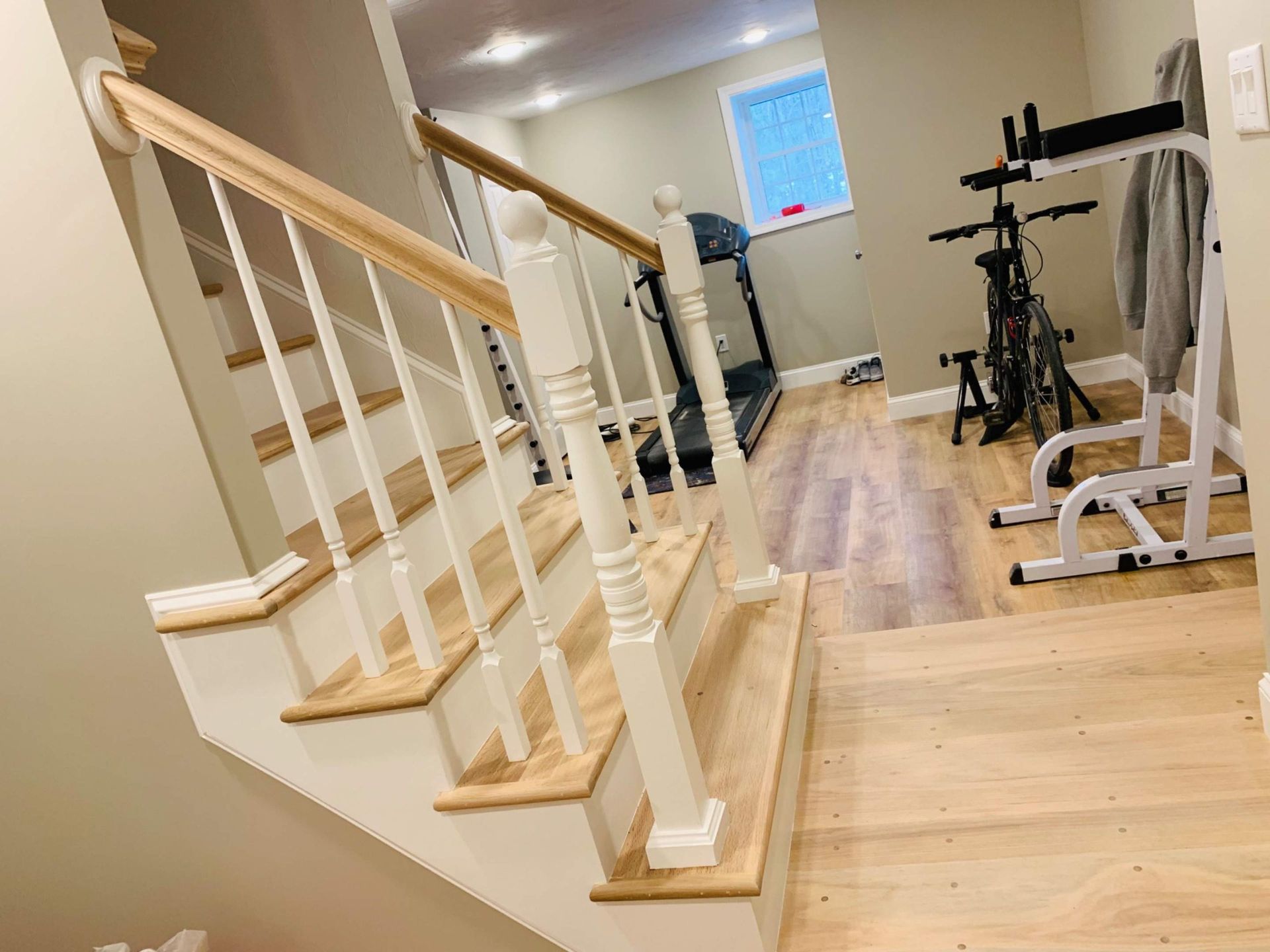 Staircase leading down to a home gym with a treadmill, bike, and exercise equipment.