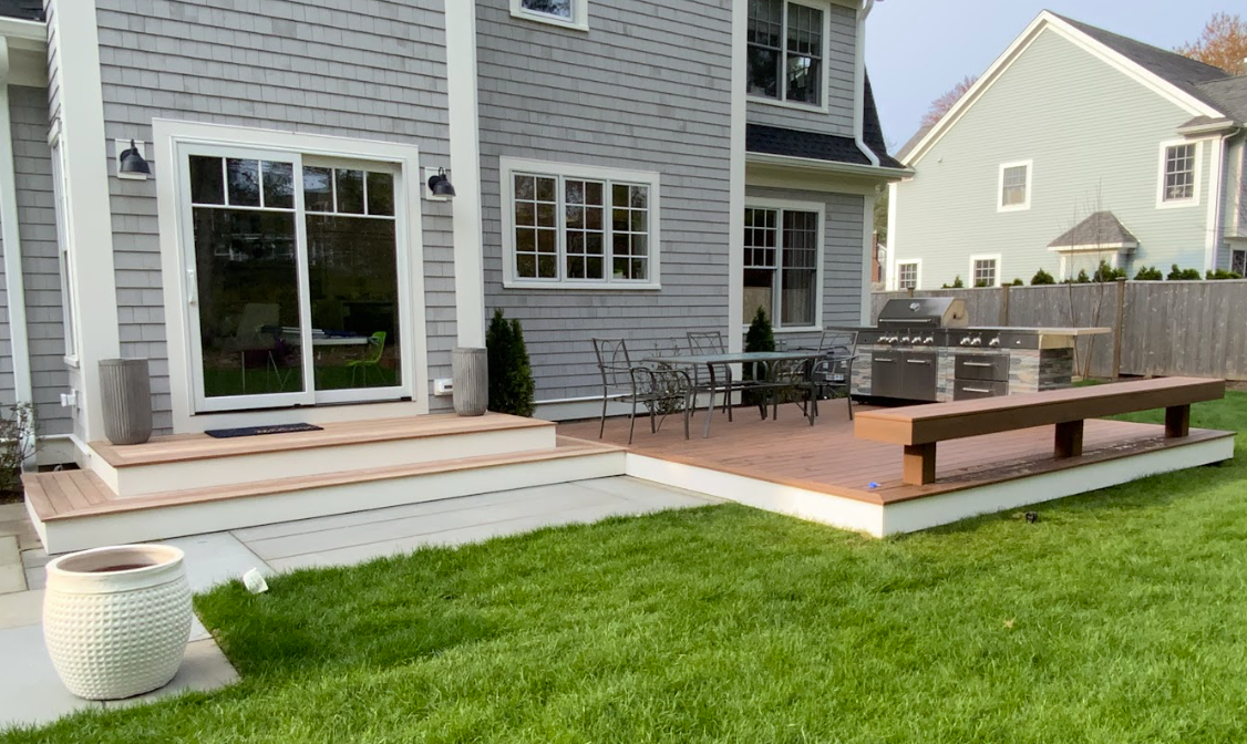 Backyard with house, deck, grass, outdoor kitchen and seating.