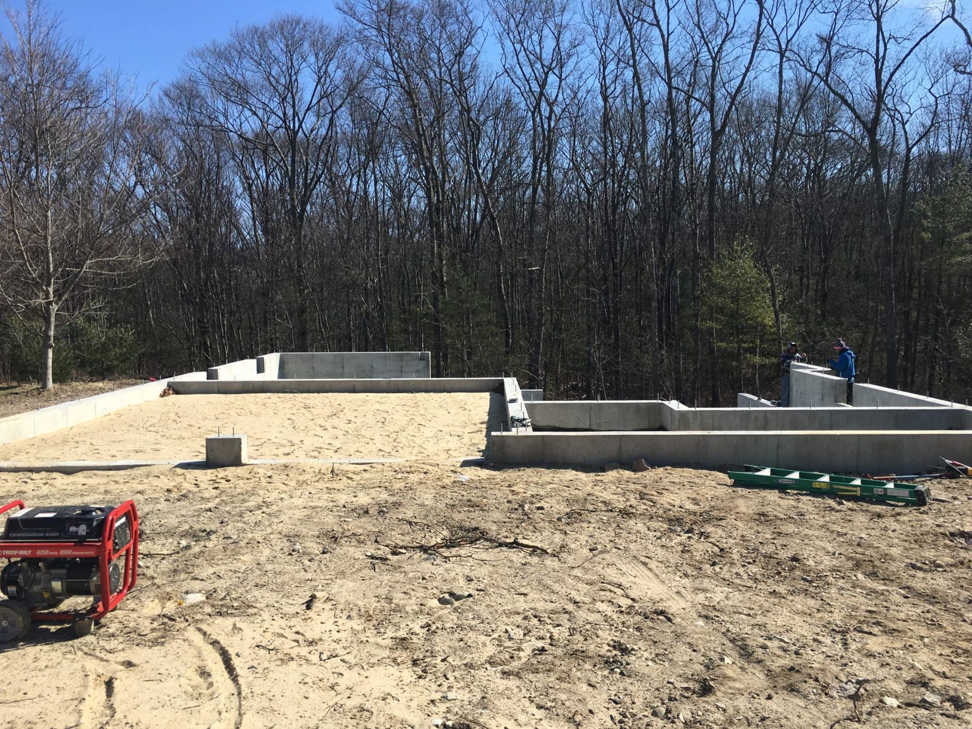 Concrete foundation of a building under construction on sandy ground.