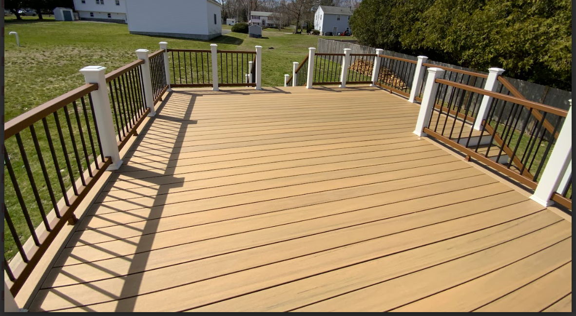 Wooden deck with brown and white railing on a grassy lawn.