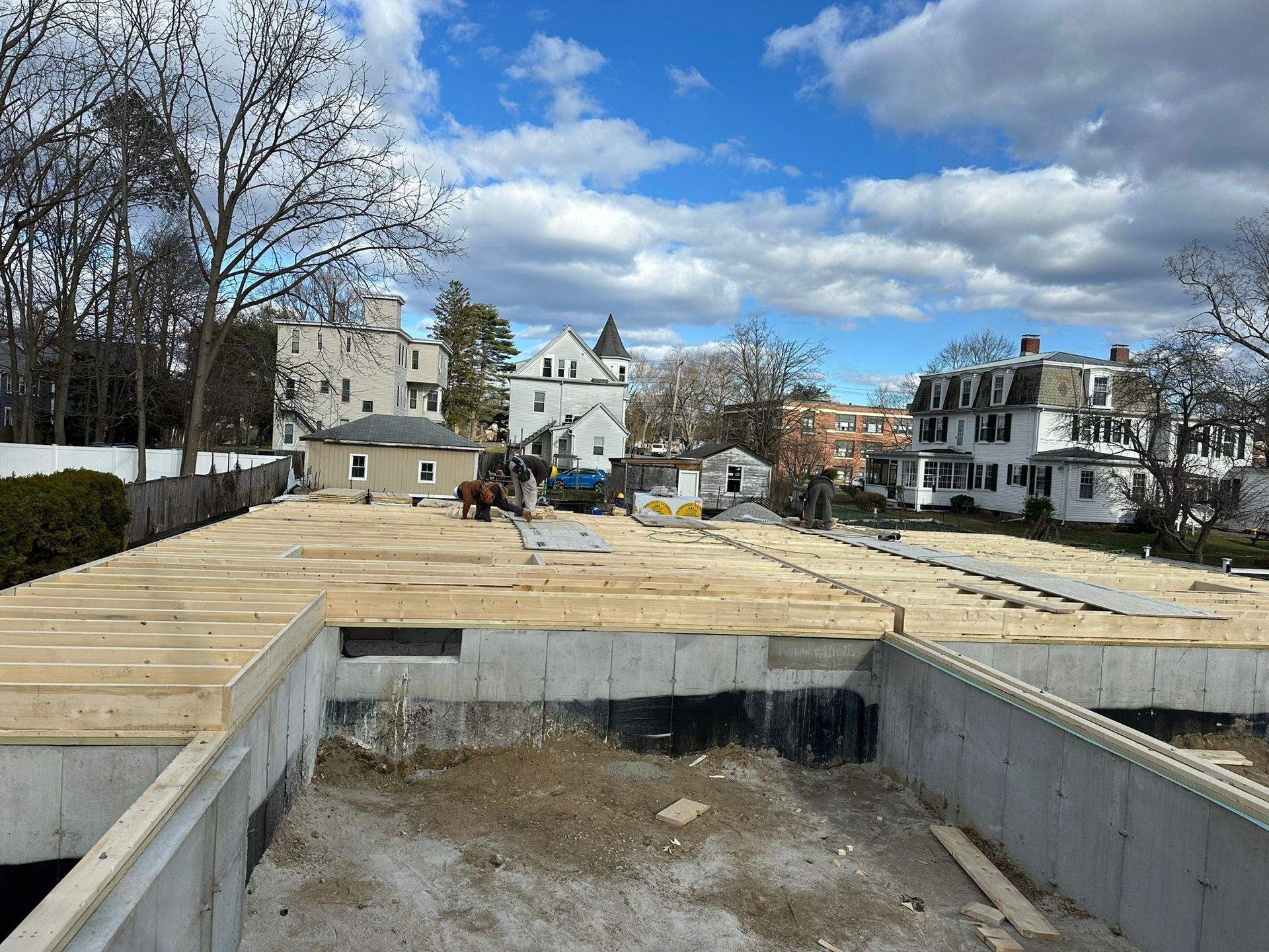 Construction site with concrete foundation and exposed wooden floor framing.