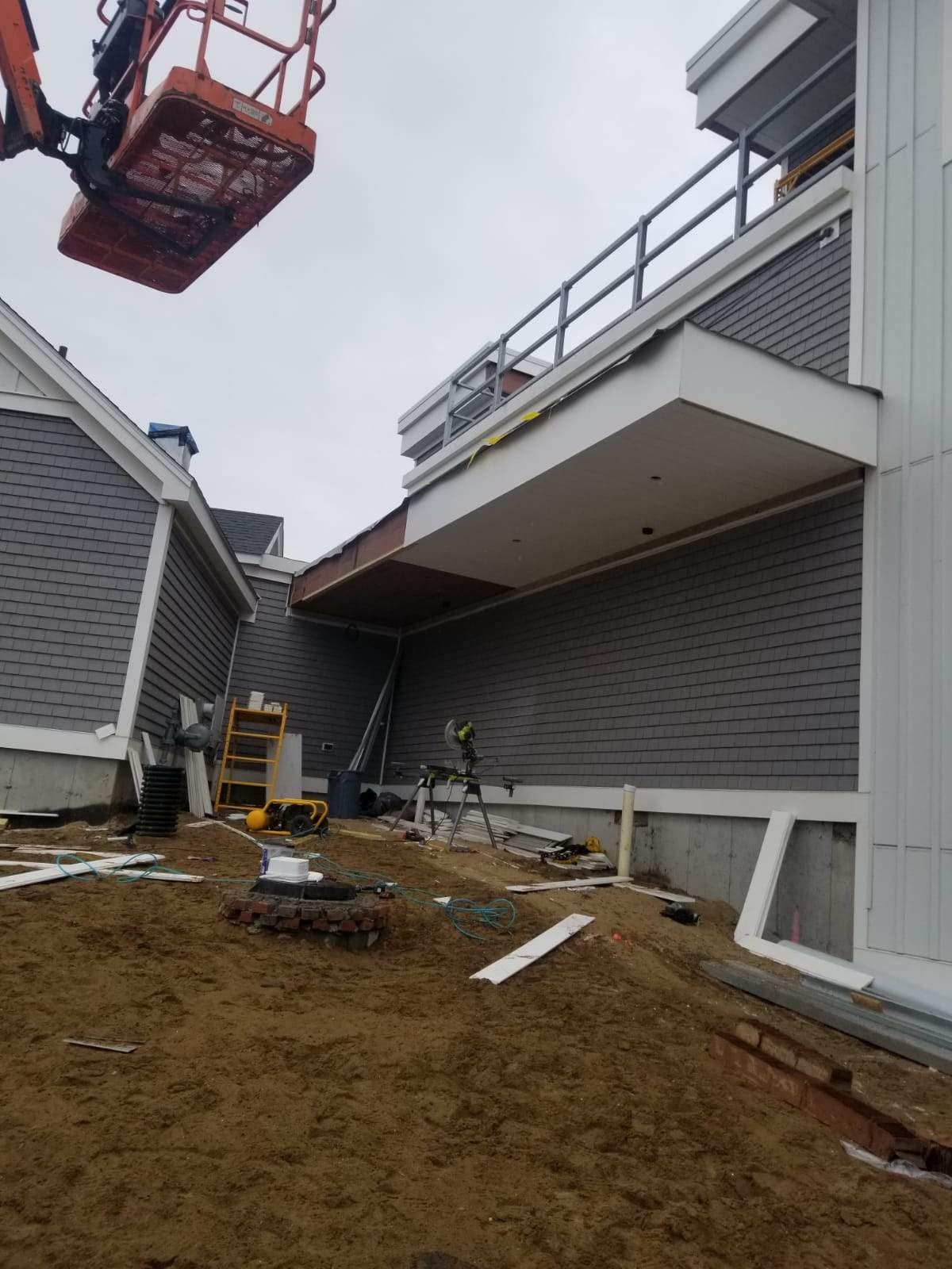 Construction site with a lift, gray siding, and exposed wood.