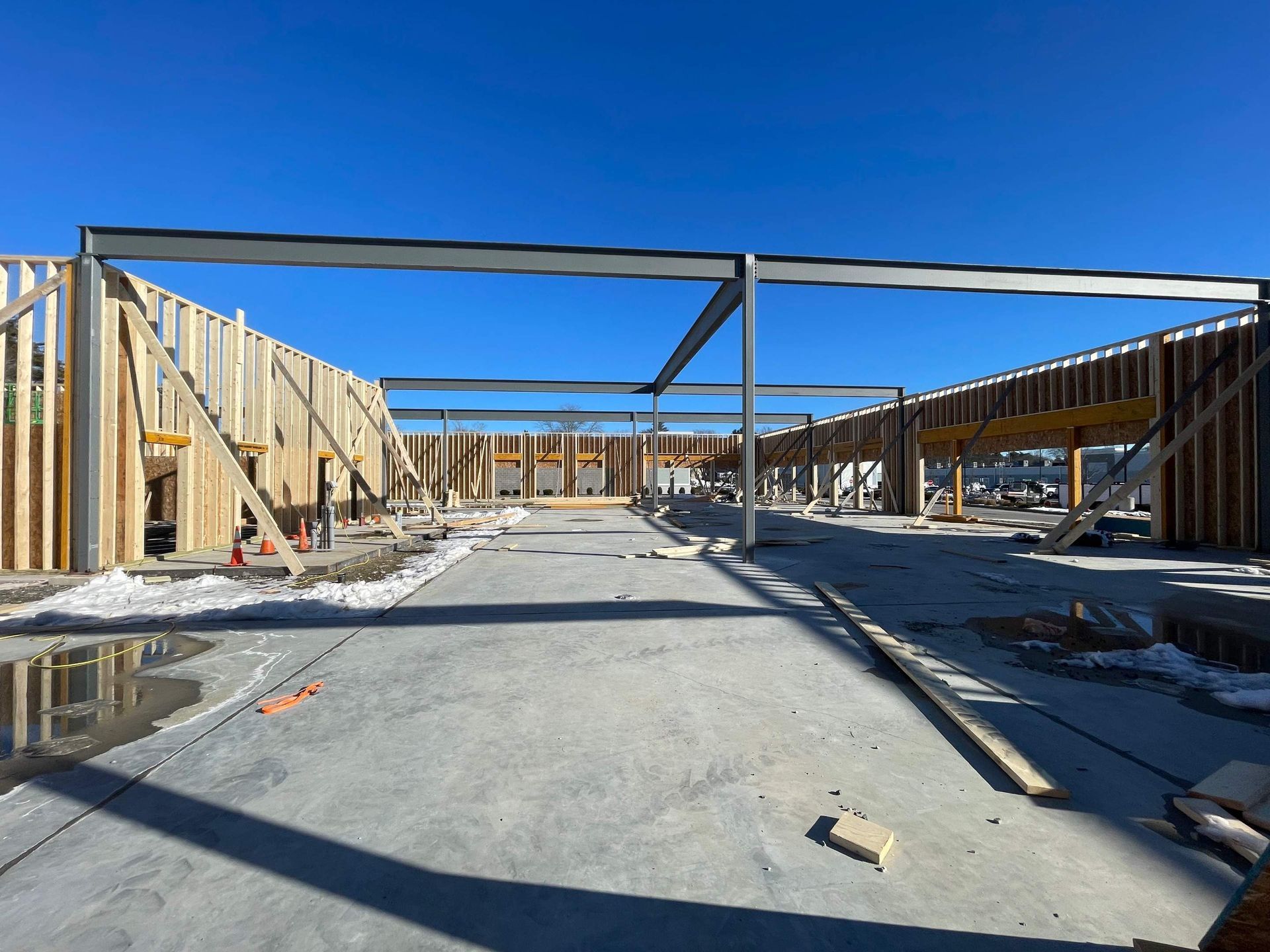 Construction site with wooden walls and steel beams against a clear blue sky.