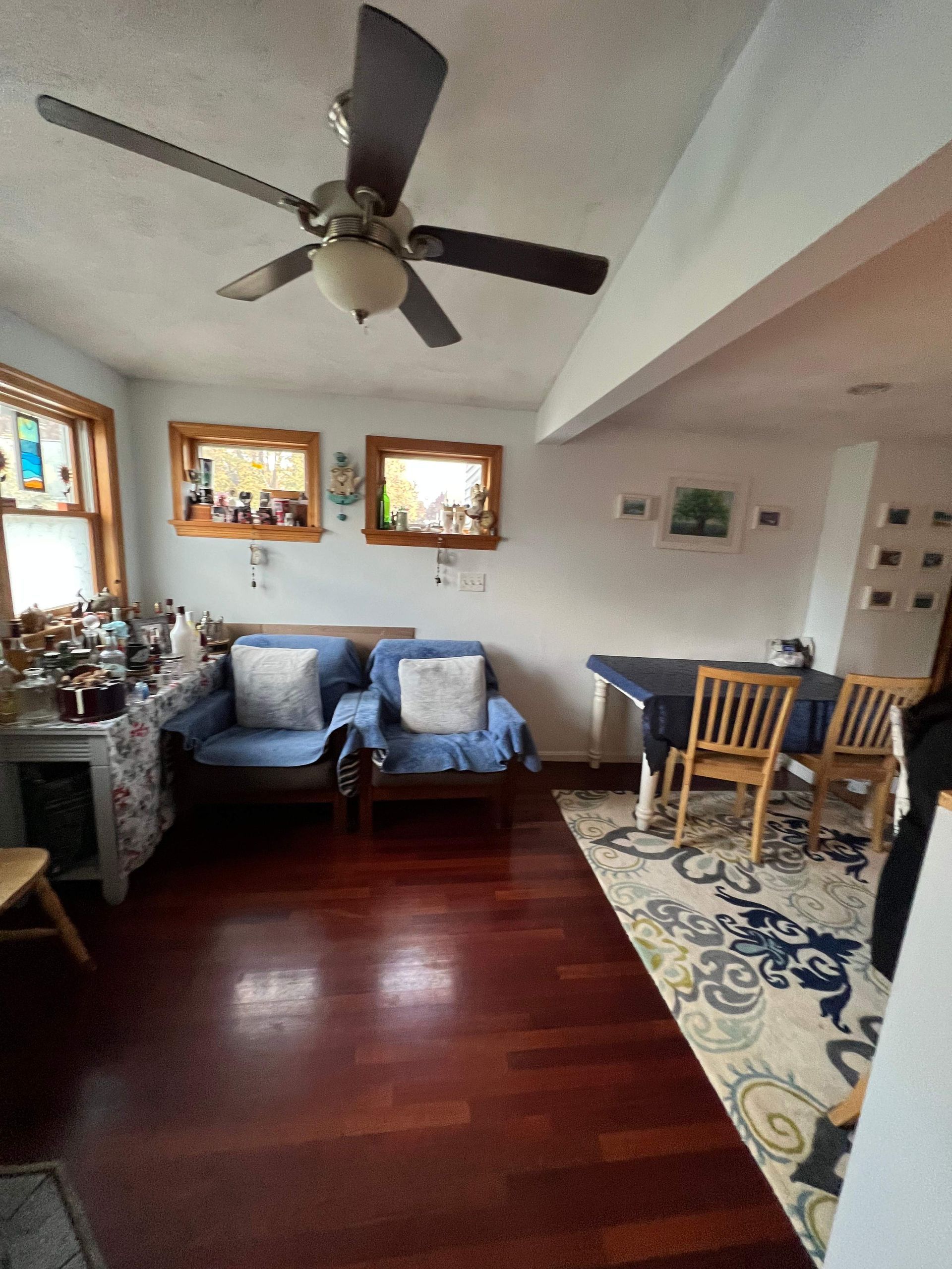 Living room with hardwood floors, two blue armchairs, and a dining table with chairs.