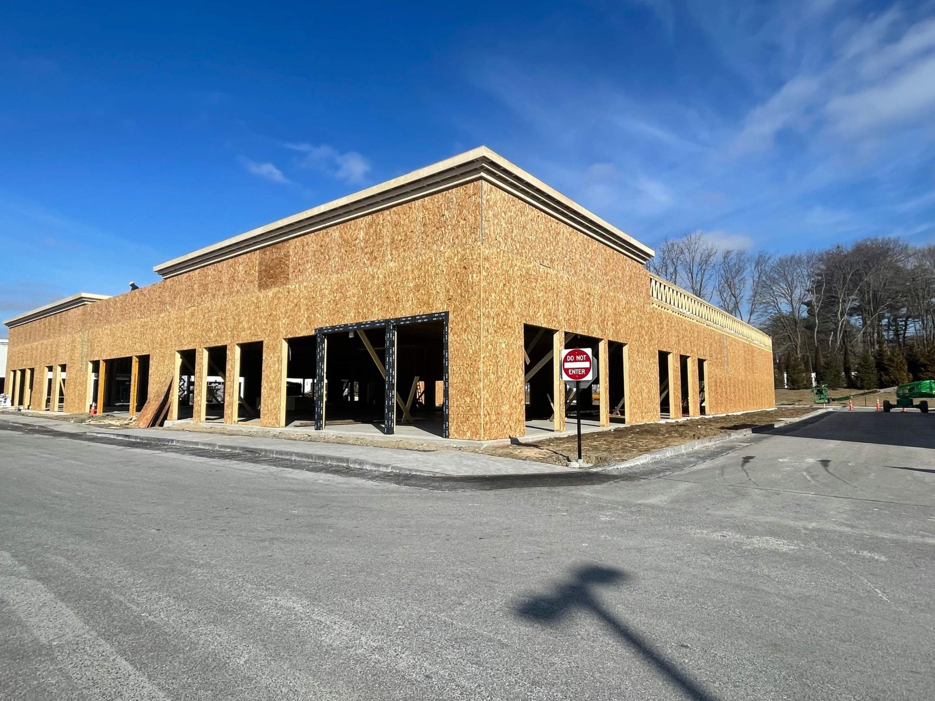 Building under construction; exterior view, light wood, large rectangular structure, many window/door openings.