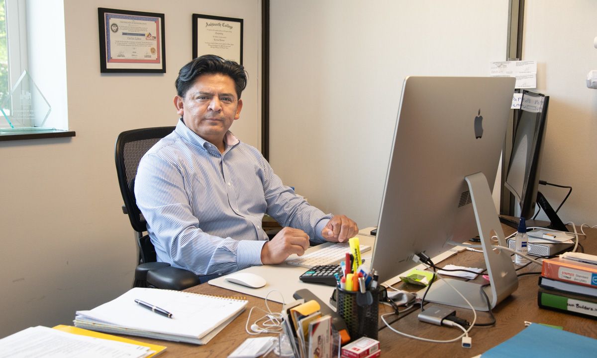Man sitting at a desk in an office, looking at the camera.