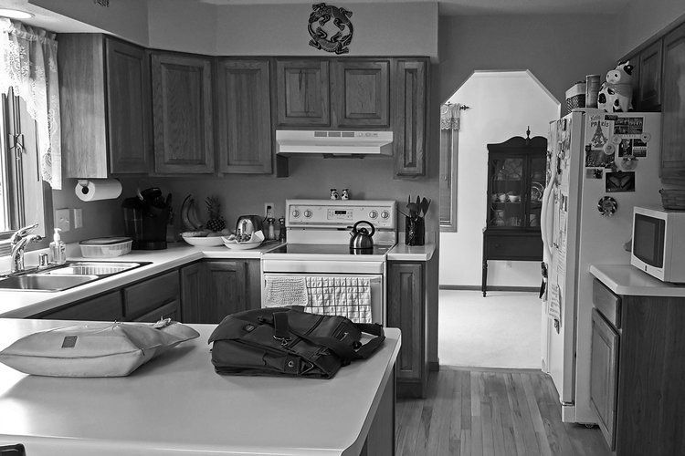 Black and white kitchen with wood cabinets, island, and appliances, including a stove, refrigerator, and microwave.