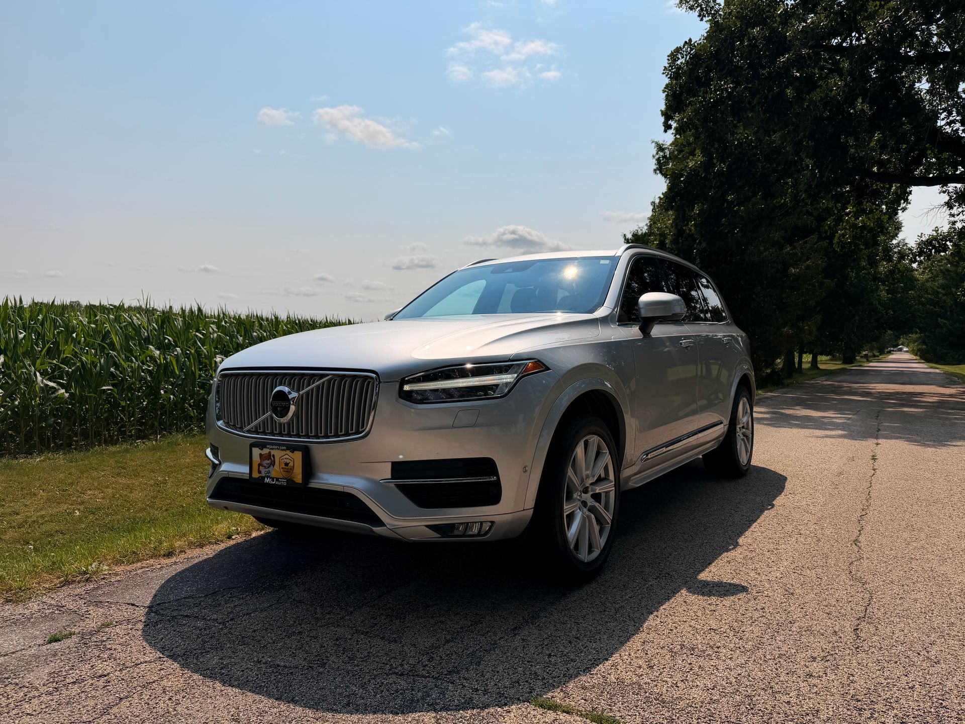 Silver Volvo SUV parked on a road beside a grassy field, with M&J Auto logo in the corner