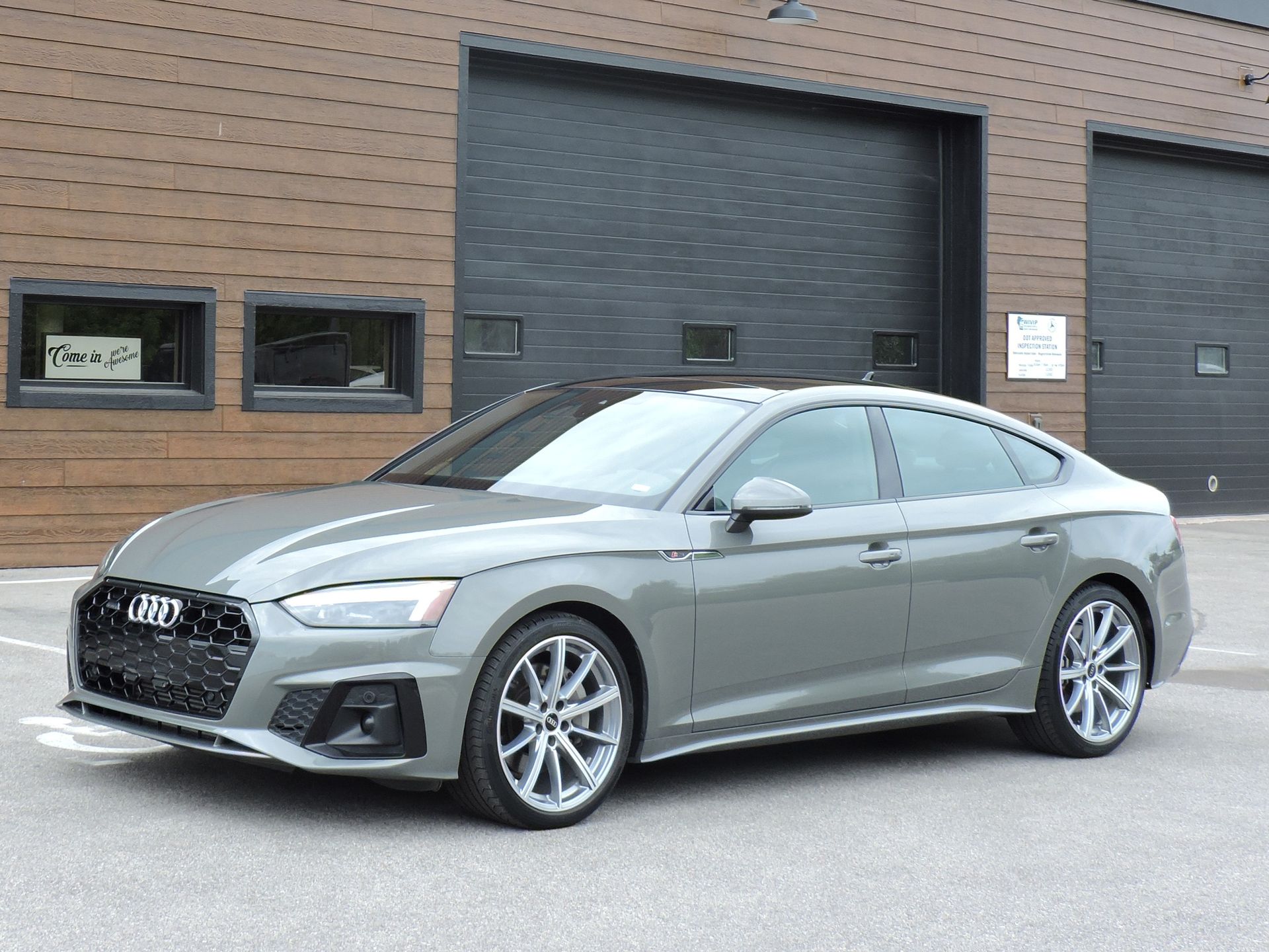 Silver Audi sedan parked in front of a brick building with garage doors.