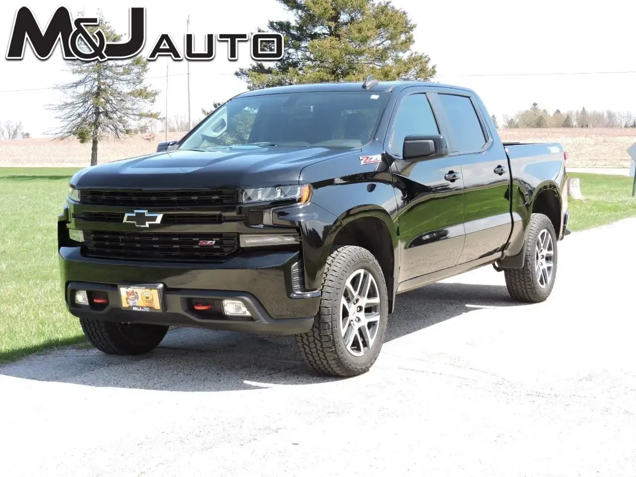 Black Chevrolet pickup truck parked on a gravel drive with M&J Auto logo in the corner