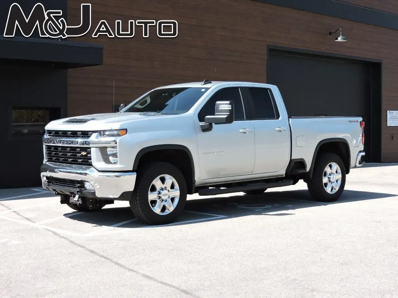 Silver pickup truck parked outside a building with M&J Auto signage.