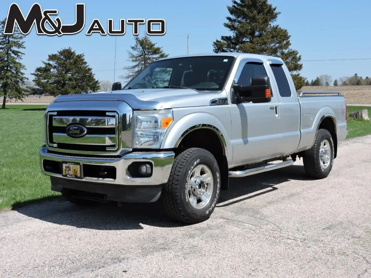 Silver Ford pickup truck parked on a road beside grass under a clear blue sky