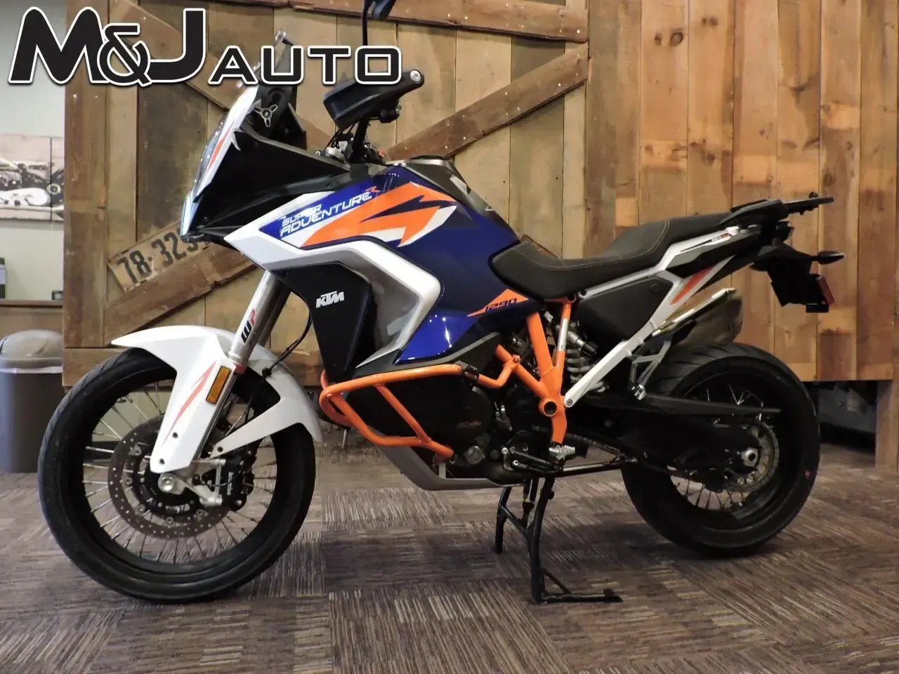 Blue, orange, and black sport motorcycle on a wooden floor in a rustic garage setting.