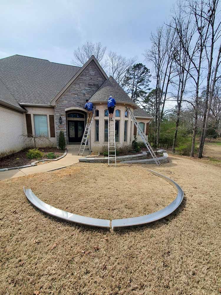 A man is standing on a ladder in front of a house.