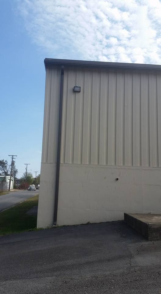 A white building with a drain pipe on the side of it.