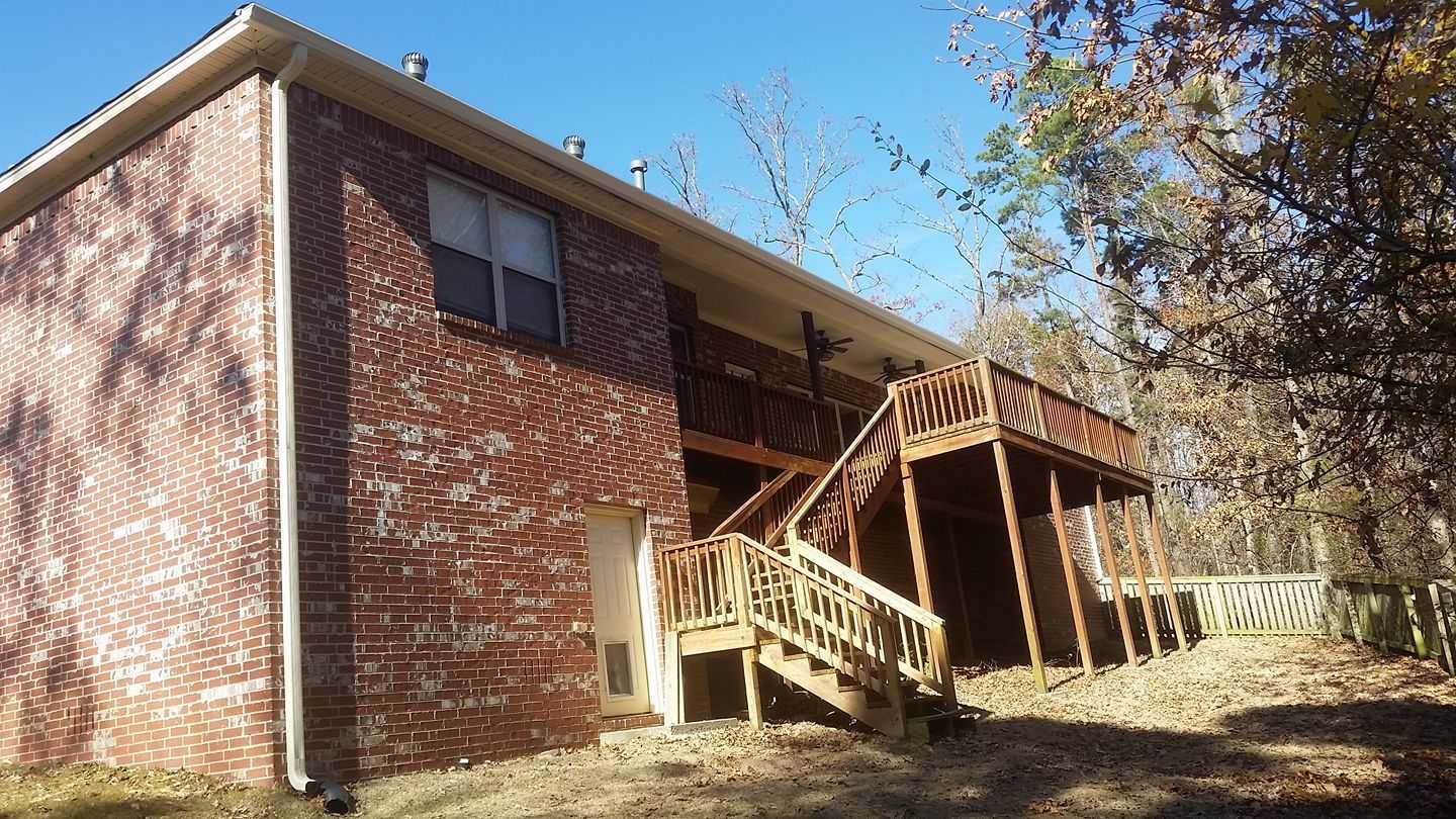 A brick house with a wooden deck and stairs.