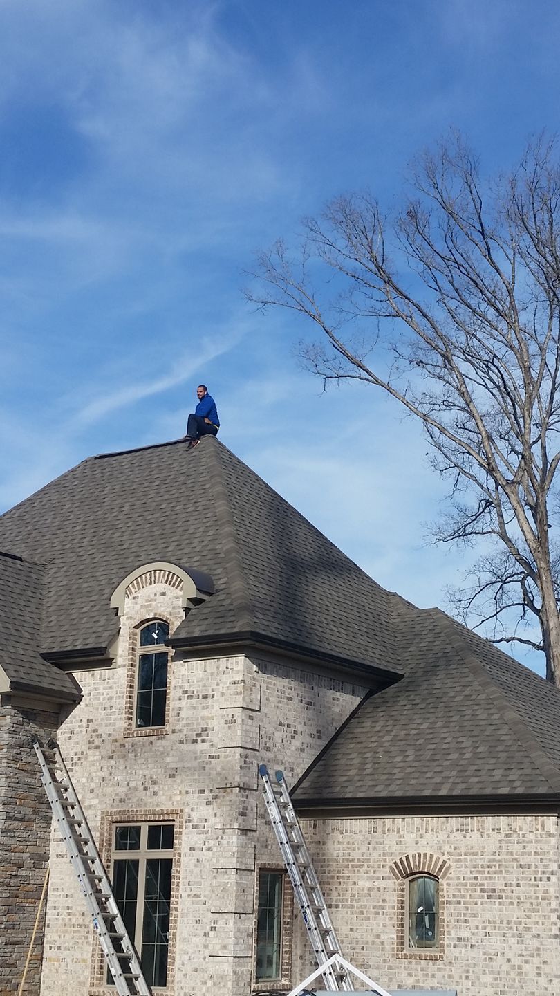 A man is sitting on the roof of a house.