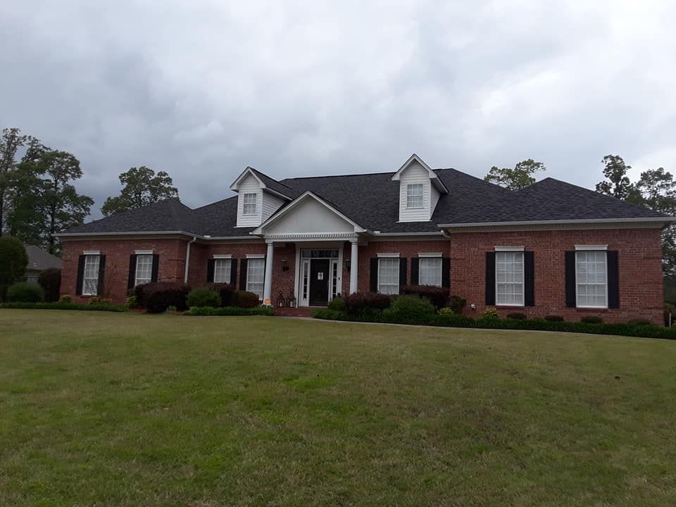 A large brick house with a black roof and white trim