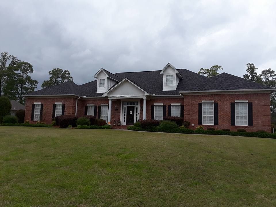 A large brick house with a black roof and white trim
