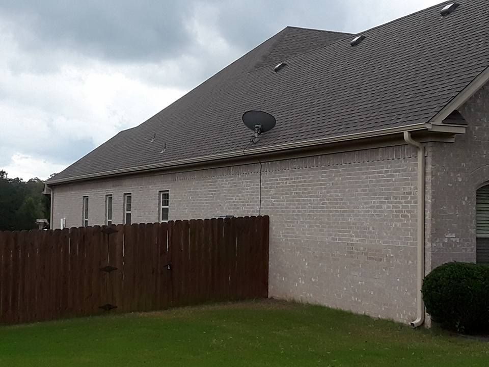 A brick house with a wooden fence and a satellite dish on the roof.
