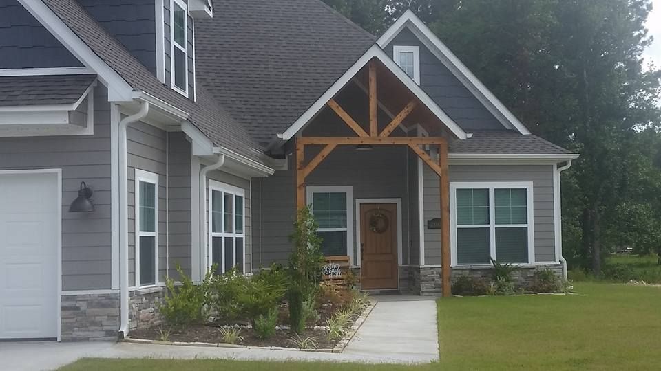A large gray house with a wooden porch and a white garage door.