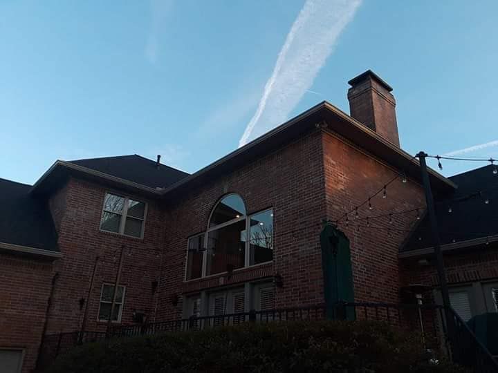 A large brick house with a black roof and a chimney.