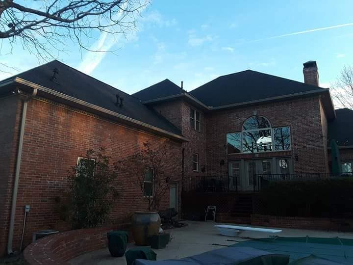 A large brick house with a pool in front of it