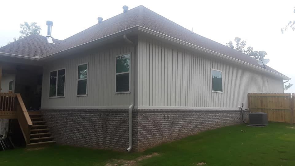 The back of a house with a lot of windows and a brick wall.