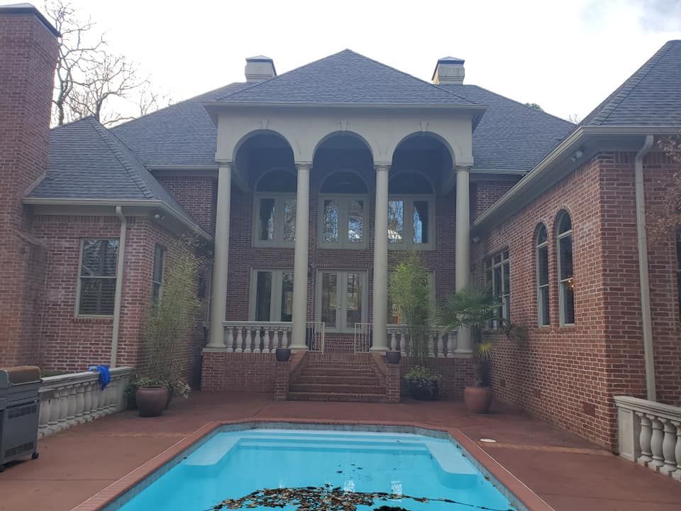 A large brick house with a swimming pool in front of it.