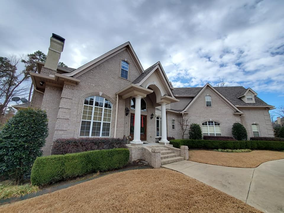 A large brick house with a gray roof and a large driveway.