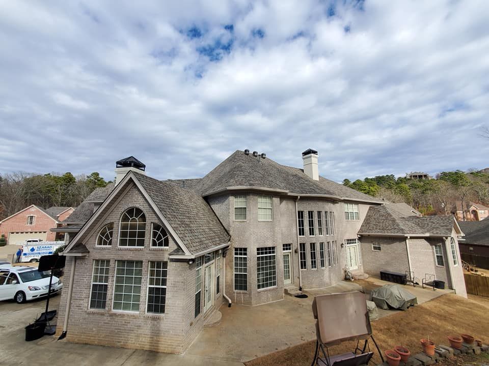 A large brick house with a gray roof and a lot of windows.