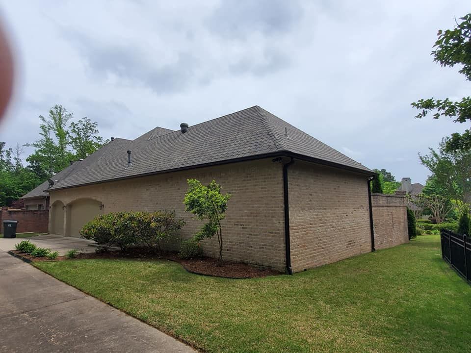 The back of a brick house with a roof and a garage.