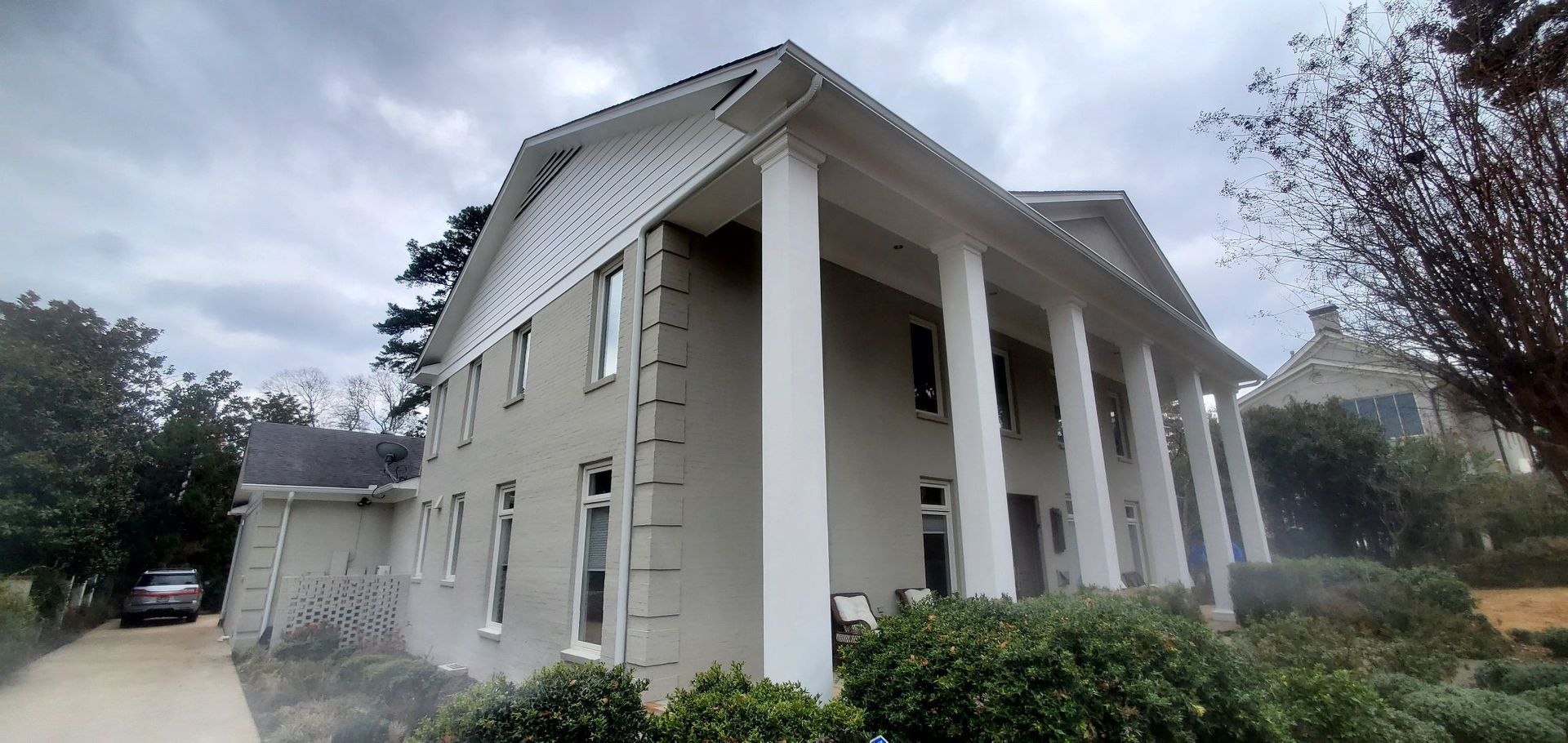 A large white house with columns and a car parked in front of it