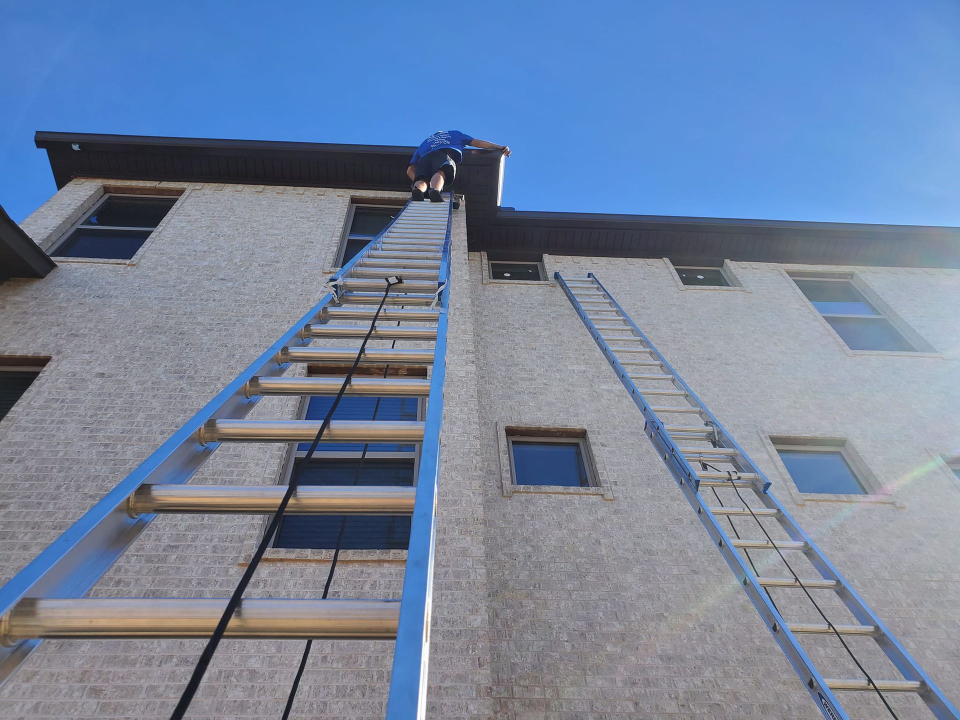 A man is climbing up a ladder on the side of a building