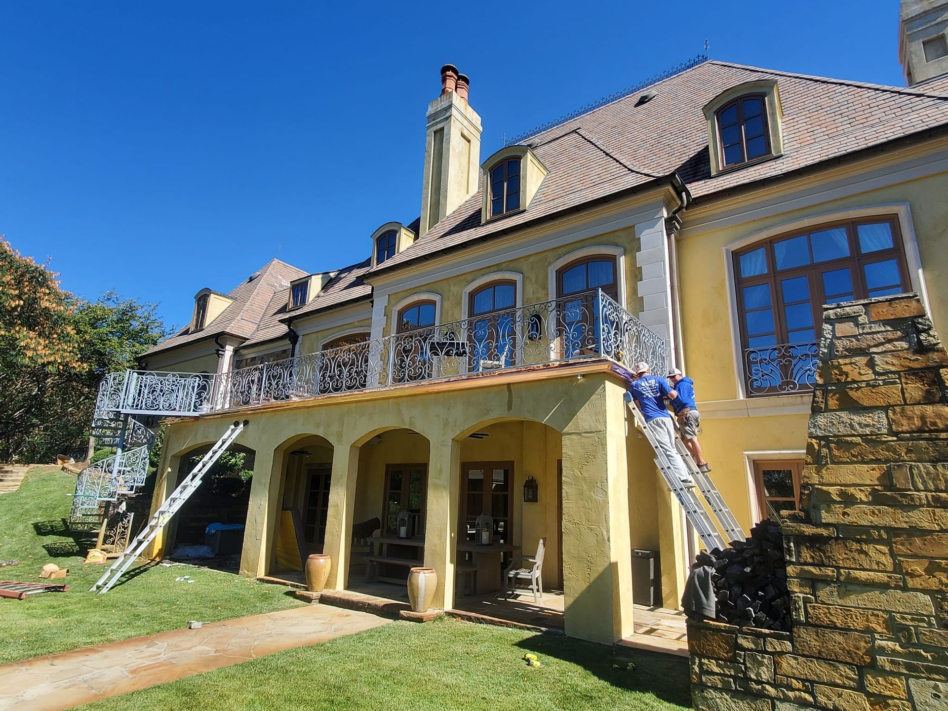 A large yellow house with a lot of windows is being painted.