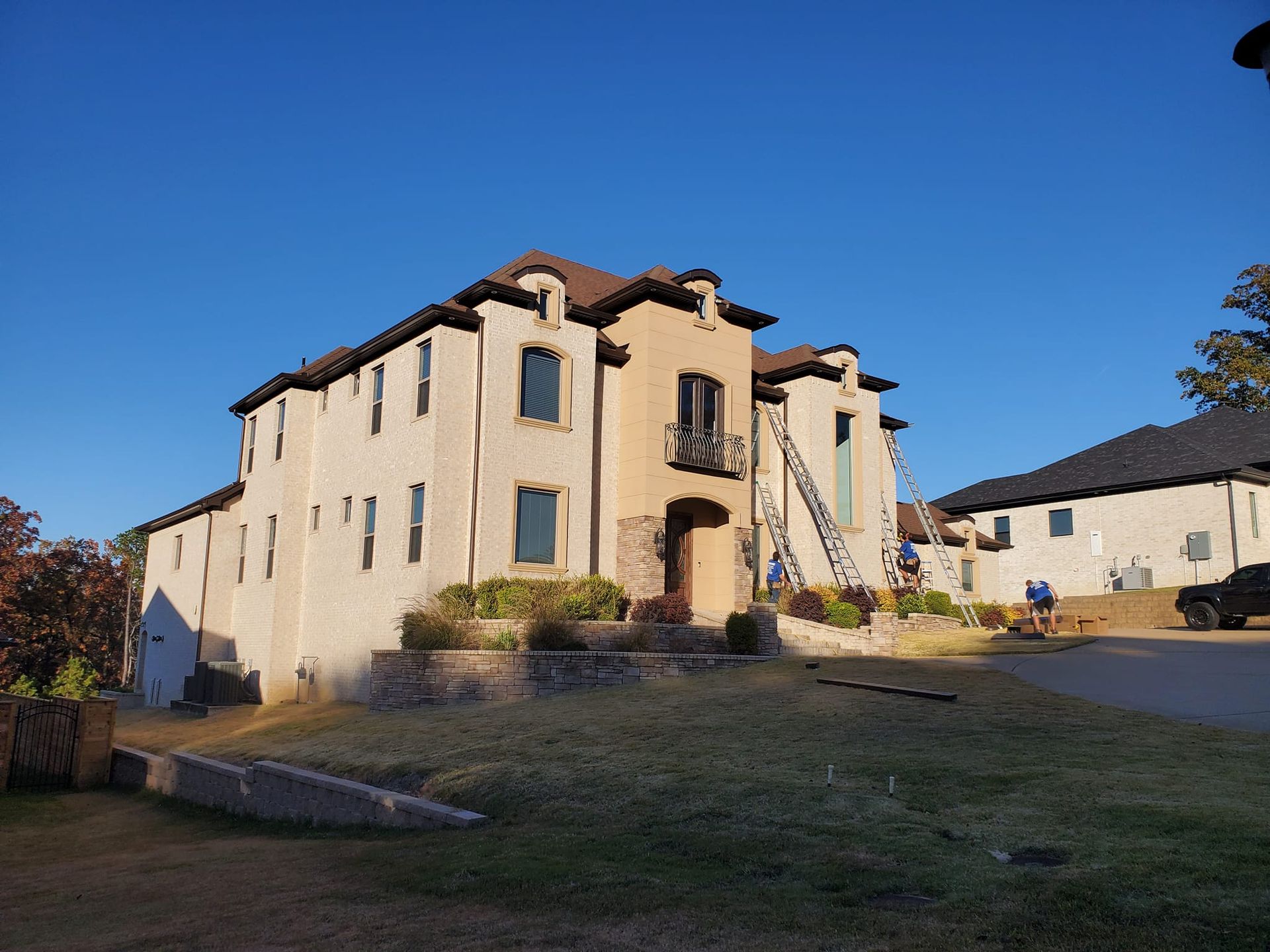 A large white building with a brown roof is sitting on top of a grassy hill.